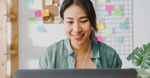 Cursos de tecnologia representado por uma mulher sorrindo em frente à tela do seu notebook